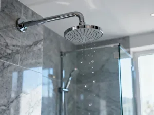 Okrągłe lustro zawieszone na betonowej ścianie nad drewnianą szafką w nowoczesnej, minimalistycznej łazience.